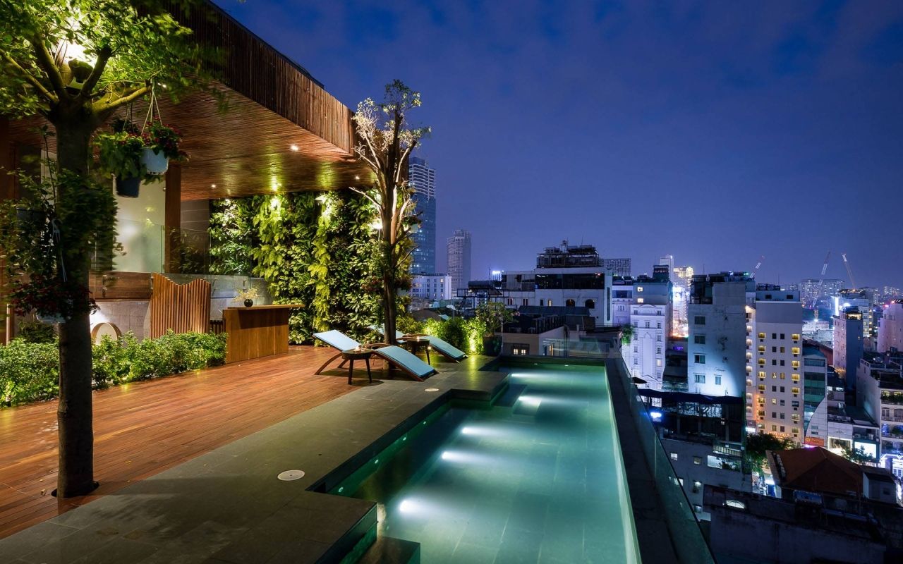 Yen Rooftop Bar: An Award-Winning Rooftop Bar in District 1 2 Yen Rooftop Bar at night, a garden rooftop bar in District 1 with planted walls, a timber deck and a lit pool facing the city