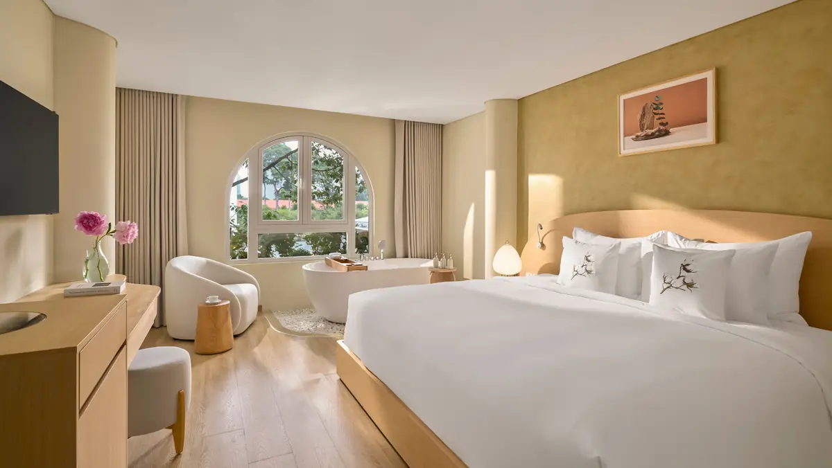 Why Are Silverland Mây's Rooms Named After Saigon's Flowers and Plants? 6 Green Papaya room at Silverland Mây, freestanding soaking tub beside an arched window