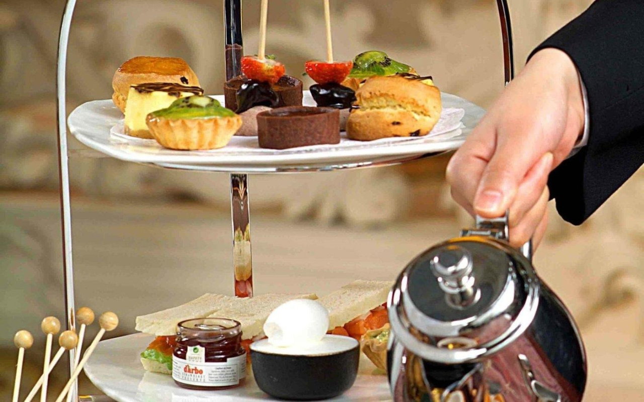 A tiered afternoon tea stand at The Nest with tea being poured