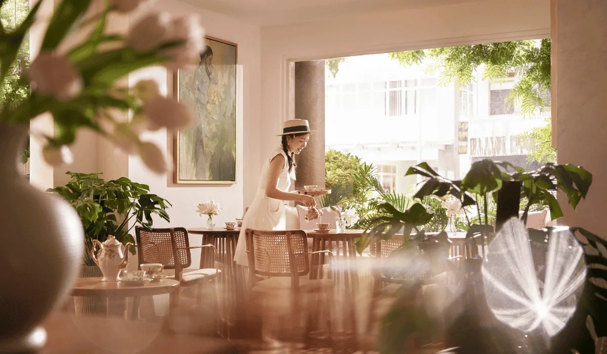 Best Coffee Shops for a Business Meeting in District 1 4 A server pouring tea at Bason Café Thi Sach with sunlight streaming through the windows