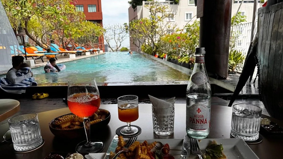 Rooftop Đẹp Nhất Để Xem Pháo Hoa Ở Sài Gòn 2 Bàn cạnh hồ bơi với cocktail tại Rooty Bar, nhìn ra hồ bơi vô cực dài 24m của The Myst Đồng Khởi
