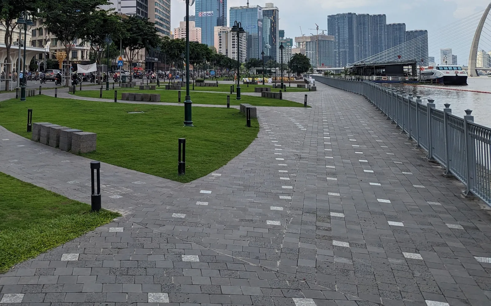 Bach Dang Wharf Park promenade along the Saigon River, with walking paths, lawns and the city skyline